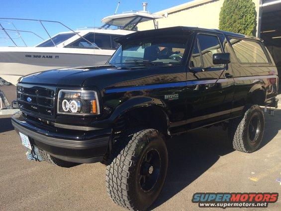 Black 1992 Ford Bronco SUV with blue pinstripes, lifted suspension, and aftermarket headlights