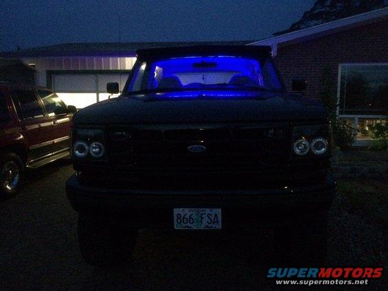 Front view of a 1992 Ford Bronco with blue interior lights. Another SUV is parked to the left