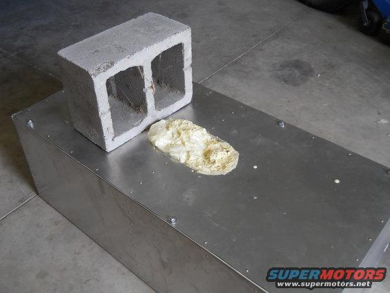 Cinder block sits on a metal box with a blob of foam next to it