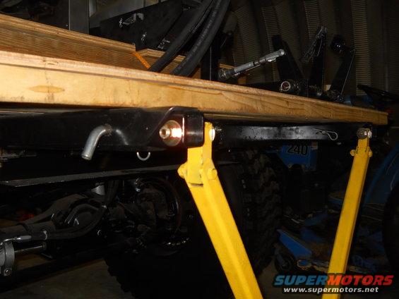 Close-up of vehicle chassis with yellow supports and wooden planking