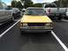 1983 Volkswagen Rabbit - Front view of a yellow 1983 Volkswagen Rabbit parked in a lot with other vehicles.