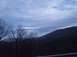 1990 Ford Bronco - A cloudy sky looms over a mountainous landscape with silhouetted trees in the foreground.
