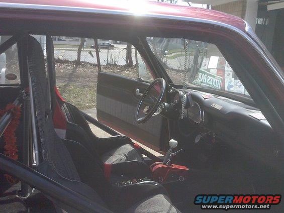 Red car interior with racing seats, roll cage, and aftermarket shifter
