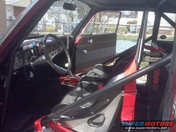 Interior view of a race car with roll cage, racing seats, and custom gauges