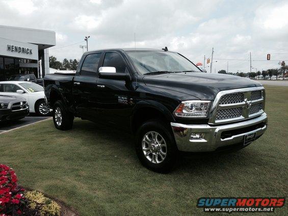 Black Ram pickup truck parked on grass in front of a dealership