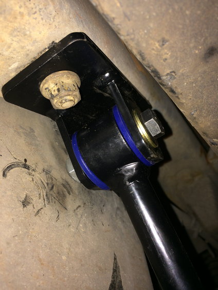 Close-up of a black sway bar mounting bracket with blue bushings and a bolt