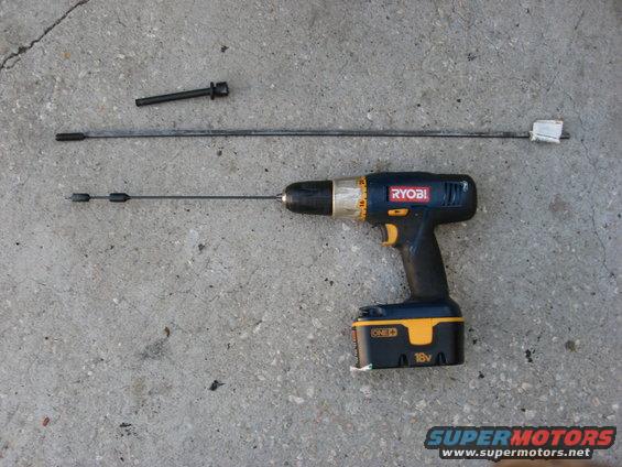 Ryobi 18V drill with two automotive cables and a bolt on concrete