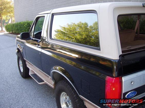 Black and tan Ford Bronco, rear three-quarter view, showing side steps and tinted windows