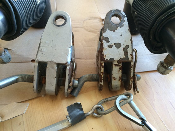 Two metal tow bar parts, one rusty, with chains and bolts