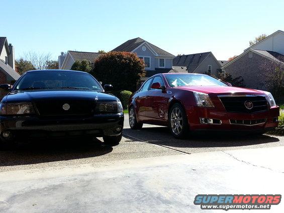 Red 2008 Cadillac CTS parked in driveway, front view, with a black car to its left