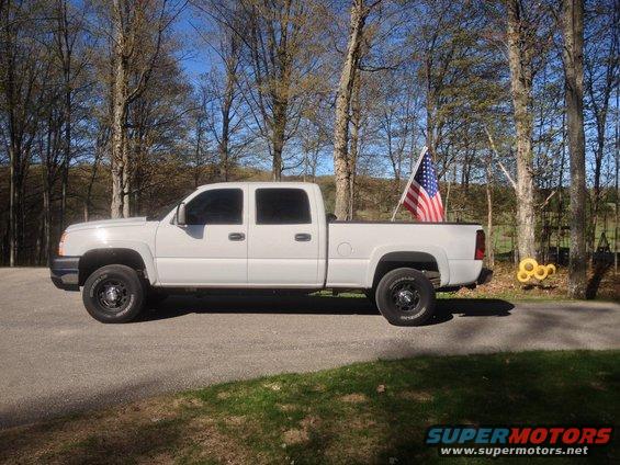 White pickup truck, side view, with an American flag in the bed