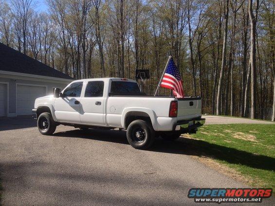 White Chevrolet Silverado pickup truck parked in driveway, American flag in bed