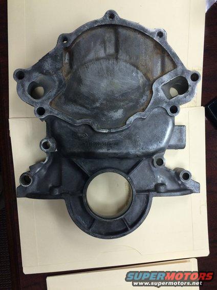 Metal engine timing cover with bolt holes and a central circular opening