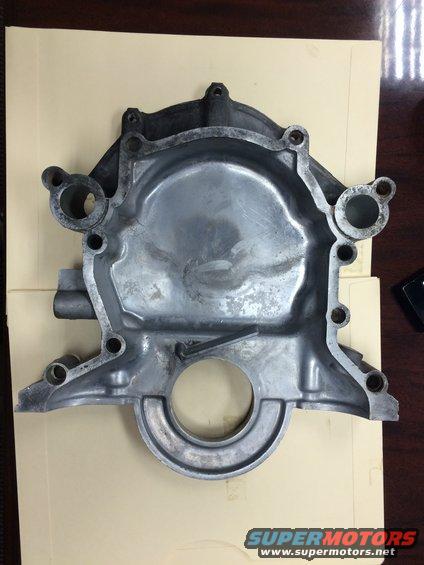 Aluminum engine timing cover with bolt holes and a central circular opening