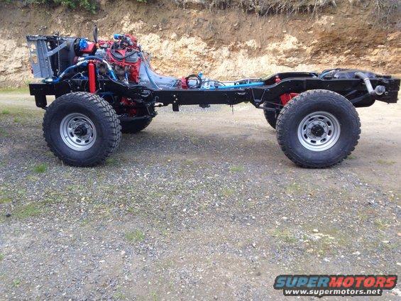 Truck chassis with engine and suspension components visible, parked on gravel