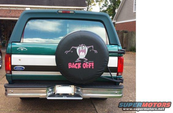Rear view of a green 1996 Ford Bronco with a spare tire cover the Tasmanian Devil saying 'Back Off!'