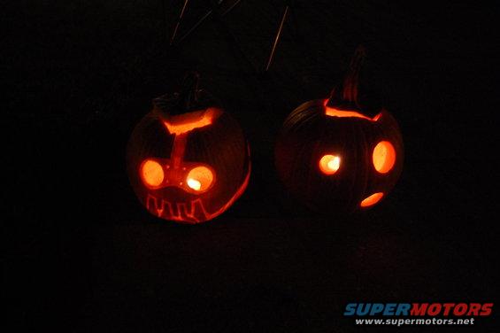 two carved pumpkins with glowing faces against a dark background