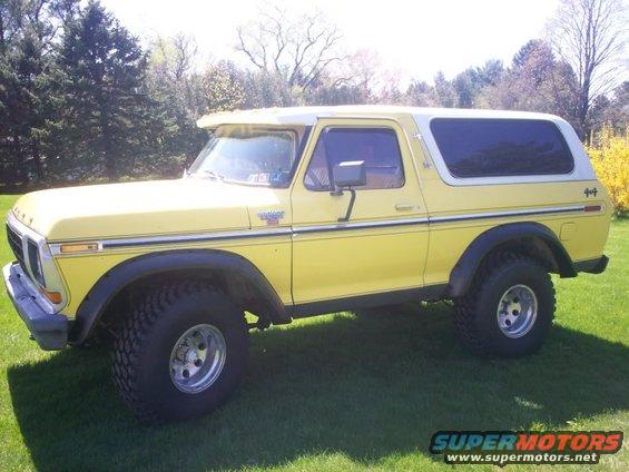 Yellow 1979 Ford Bronco with white top parked on grass
