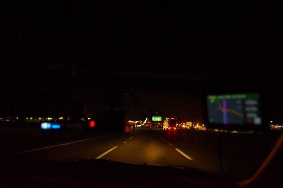 Dashboard view at night with GPS screen showing navigation, highway lights in distance
