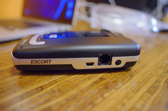 Escort radar detector with USB and RJ11 ports on a wooden surface