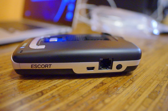 Escort radar detector on wooden table, side view showing ports and branding