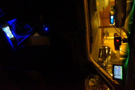 Car interior at night with a phone charging and a GPS device mounted on the windshield