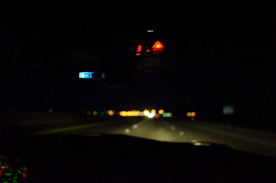 Car interior at night, dashboard lights and rearview mirror display visible