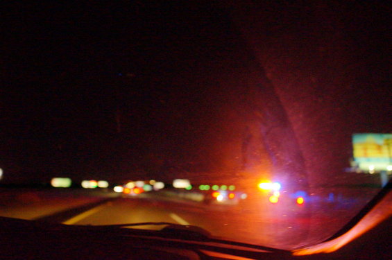 Highway at night with flashing emergency lights and distant traffic