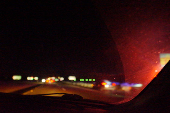 View from inside a vehicle looking out at a highway at night with other cars visible