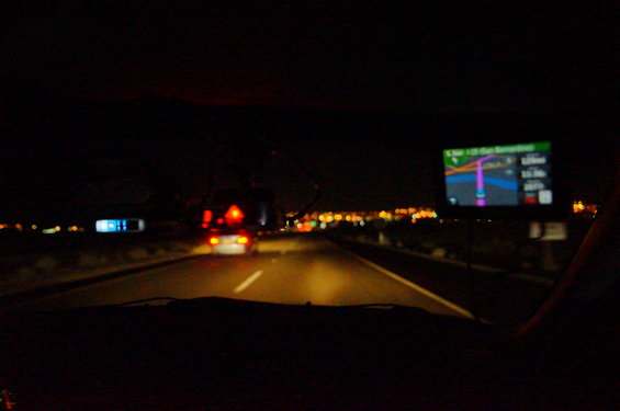 View from car interior at night showing GPS screen and road ahead with other vehicles