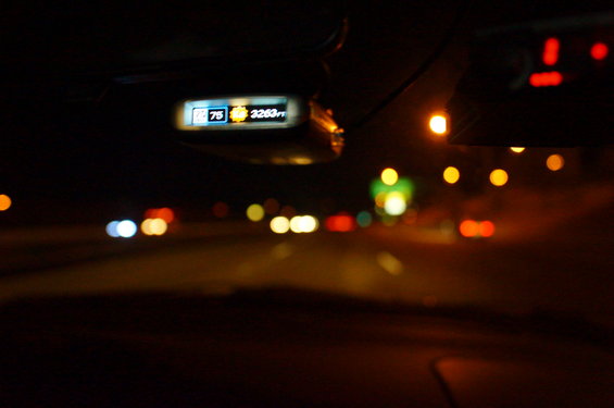 Dashboard display shows 75 degrees and 3263 ft. Highway traffic at night is blurred