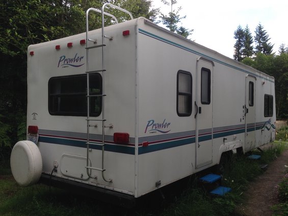 RV trailer with ladder on back, spare tire, and 'Prowler' graphics