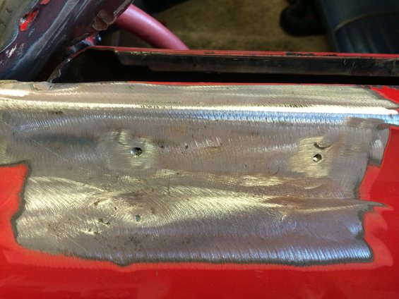 Close-up of a metal panel with fresh welds and two small holes