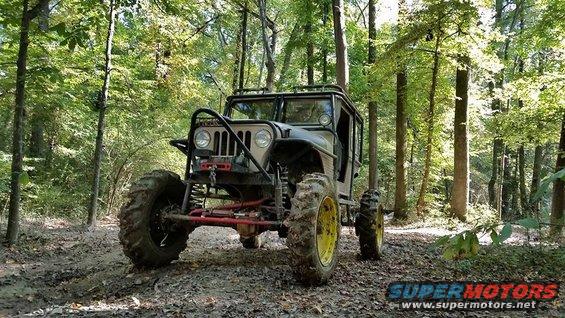 Modified jeep with large tires on a muddy forest trail