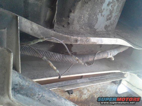 Close-up of a vehicle's underbody wiring harness with protective corrugated tubing