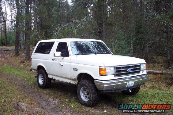White Ford Bronco parked on a dirt road in a wooded area