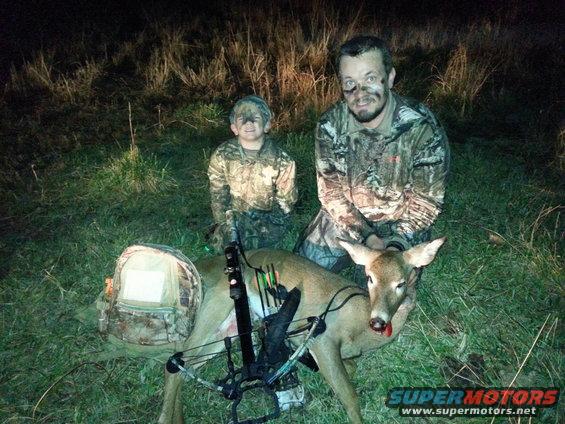 Deer with hunters and crossbow, camouflage clothing, grass and brush background, night lighting