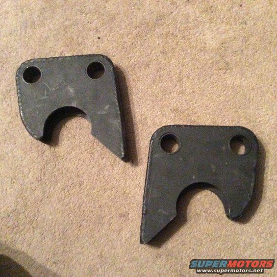 Two dark gray metal brackets with two holes each and a curved cutout