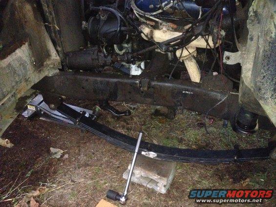 close-up of vehicle engine and leaf spring suspension with a socket wrench on a cinder block