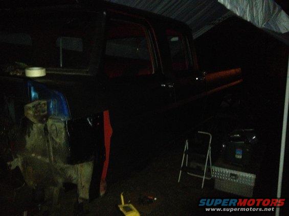 1971 Ford F-250 truck, dark color, under a tarp, side view, undergoing repairs