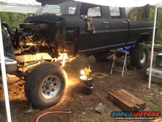 Crew cab pickup truck, engine removed, being worked on outdoors