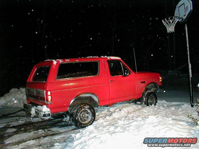 Red SUV stuck in snow with a basketball hoop in the background