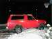 1990 Ford Bronco - A red 1990 Ford Bronco with a lifted suspension is parked in the snow at night.