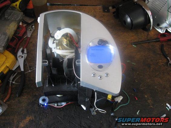 Silver and white coffee maker disassembled on a wooden workbench with tools