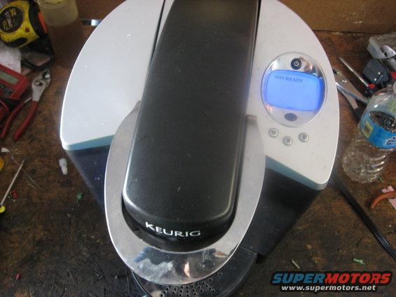 Keurig coffee maker on a workbench with tools nearby. The screen says 'NOT READY'