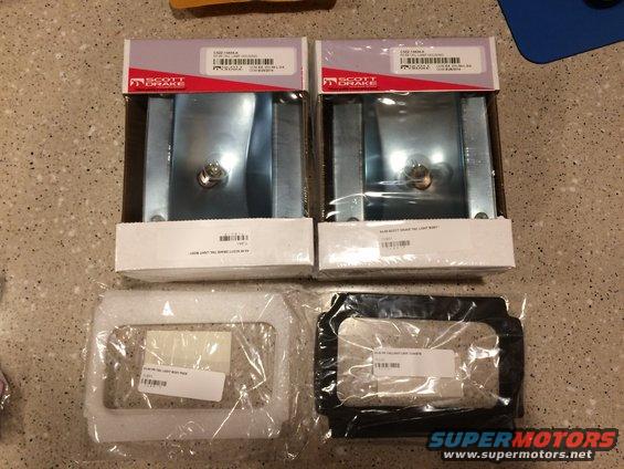 Two Scott Drake tail light assemblies in boxes and two tail light bezels in plastic packaging on a speckled countertop