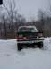 1990 Ford Bronco - A red 1990 Ford Bronco is seen from the front, partially buried in snow.
