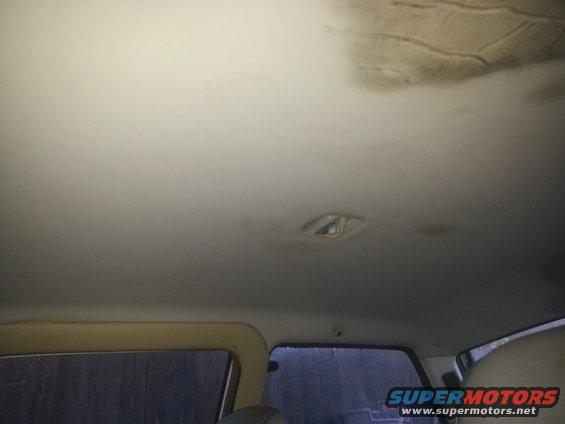 Interior view of a car's headliner with stains and a light fixture