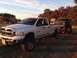 1979 Ford Bronco - A Ford Bronco is towed by a white pickup truck during golden hour, with autumn trees in the background.