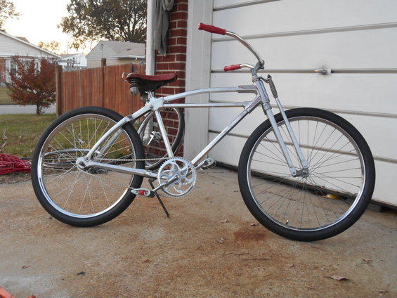Chrome bicycle with red handlebars and seat, parked in front of a garage